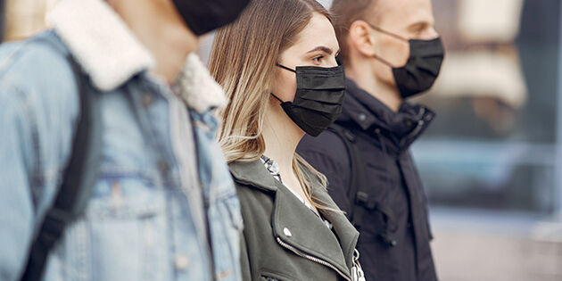 People in a masks stands on the street